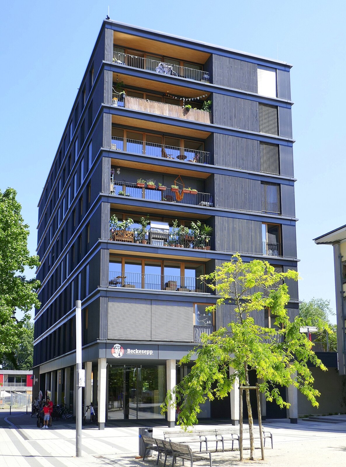 Freiburg-Weingarten, Holzhochhaus mit 8 Etagen, Baujahr 2022-23, beherbergt einen Einkaufsmarkt, eine Kita und 30 Wohneinheiten, Juni 2023