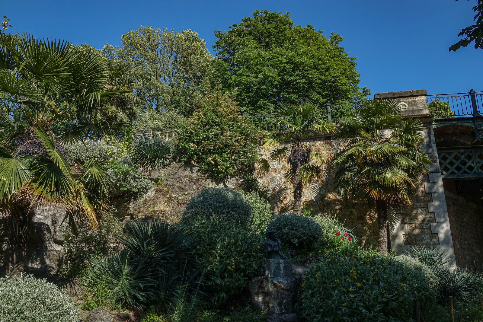 Gehweg zwischen Pflantzen im Parc des Buttes Chamount in Paris. Foto: Juni, 2023.