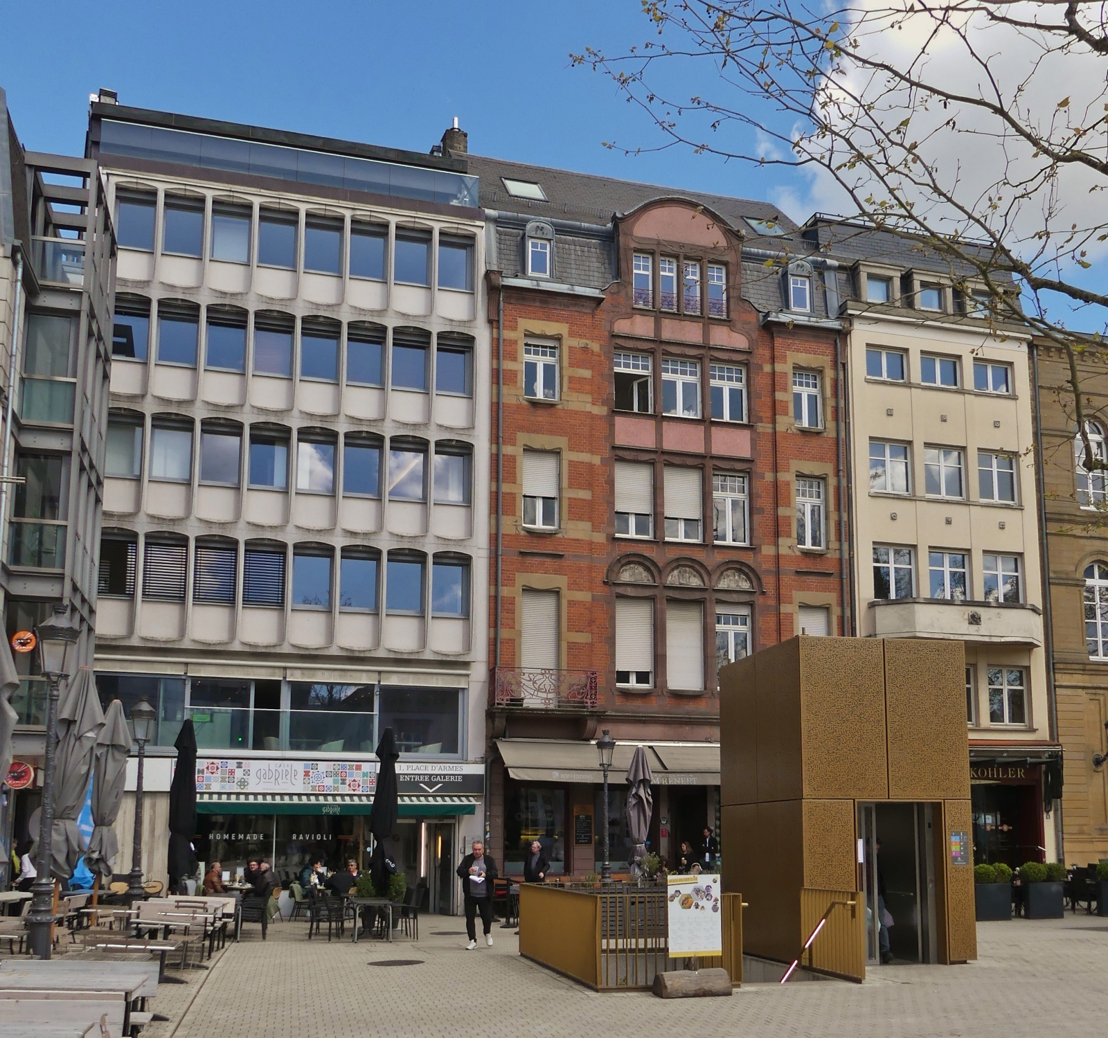 Unterschiedliche Fassaden an der Place Guillaume II mit dem Vordergrund den Lift zum Parkhaus unter dem Platz. 04.2024