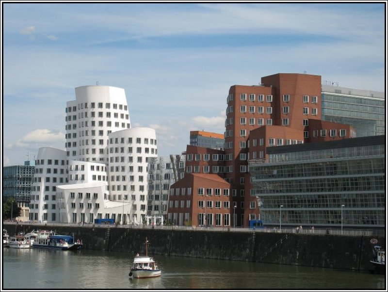 1998 bzw. 1999 wurden die sogenannten Gehry-Bauten im Dsseldorfer Medienhafen fertiggestellt. Es handelt sich dabei um drei uerst ungewhnlich gestaltete Turmkomplexe, die von dem Stararchitekten Frank Owen Gehry entworfen wurden. Die Bauten sind schief und krumm, mit unterschiedlicher Fassadengestaltung (weier Antrich, Spiegel-Fassade, Backsteine), aber irgendwie spannend. In Allen drei Gebuden sind Bros angesiedelt. Diese Aufnahme stammt vom 08.07.2007 von wurde von der Fugngerbrcke zwischen der Strae „Am Handelshafen“ und der Spitze der Speditionstrae aus gemacht. 