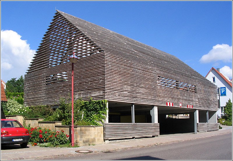 Architekturmoderne in einer kleinen lndlichen Gemeinde in Hohenlohe: Das Parkhaus an der vielbefahren Bundesstrae 290 in Rot am See wurde formal der drflichen Satteldachbebauung angepasst. Es wird aber nicht so angenommen wie erwartet, die Autofahrer stellen ihr Fahrzeug eher an den Straenrand und teilweise auf den Gehweg. 31.7.2005 (Jonas)