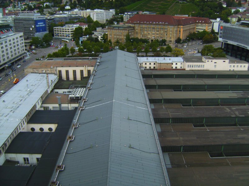 Ausblick vom Bahnhofsturm auf das noch bestehende Dach der groen Schalterhalle des Stuttgarter Hbf, welches in absehbarer Zeit dem Bau des neuen Durchgangsbahnhofs im Rahmen von Stuttgart 21 zum Opfer fallen wird. Im Hintergrund ist das ehemalige Bahndirektionsgebude zu sehen, das dem gleichen Projekt wohl ebenfalls zum Opfer fallen wird. Aufnahme vom 04.09.09