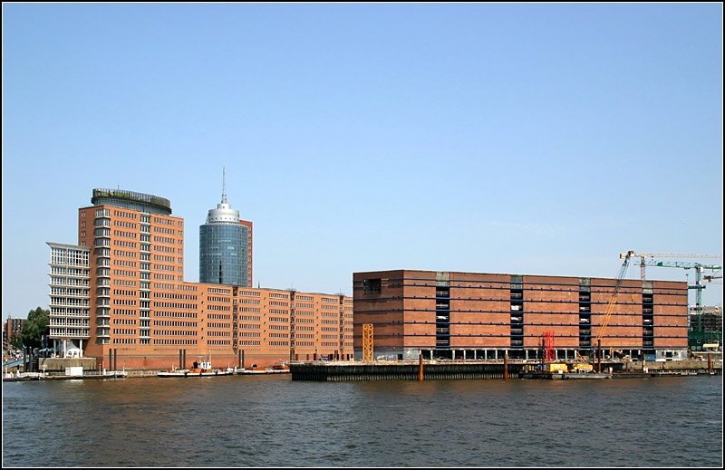 Bebauung Sandtorhft, dahinter das Hochhaus des Hanseatic Trade Centers, rechts ein alter Speicher. Auf diesem Speicher aufgesetzt wird die Elbphilharmonie, ein Bauwerk das alles in den Schatten stellen wird, was es bisher in Hamburg gibt. Der alte Speicher wird zum Parkhaus ausgebaut und darauf entsteht ein bis zu 16 Stockwerk hohes Gebude mit geschwungener, an Wellen erinnernte Dachlinie. Neben der Konzerthalle werden darin auch Wohnungen und ein Hotel untergebracht. Architekten sind Herzog und de Meuron aus Basel, die in Mnchen die neue Allianzarena bauten und auch durch den Umbau eines riesigen Elektrizittswerkes in London zur Tate Gallery of Moderne Art von sich reden machten. 15.7.2007 (Matthias)