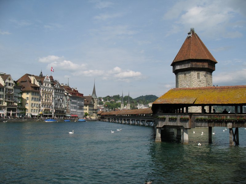 Blick auf einen Teil von Luzern und der Kapellebrcke.
Die Brcke ist mit ihren 204,70 Metern die lteste und zweitlngste berdachte Holzbrcke Europas. Der Brand im August 1993 zerstrte einen Grossteil der Brcke. Restauriert wurde sie im April 1994 erneut eingeweiht und fr den Fussgngerverkehr wiedererffnet. 