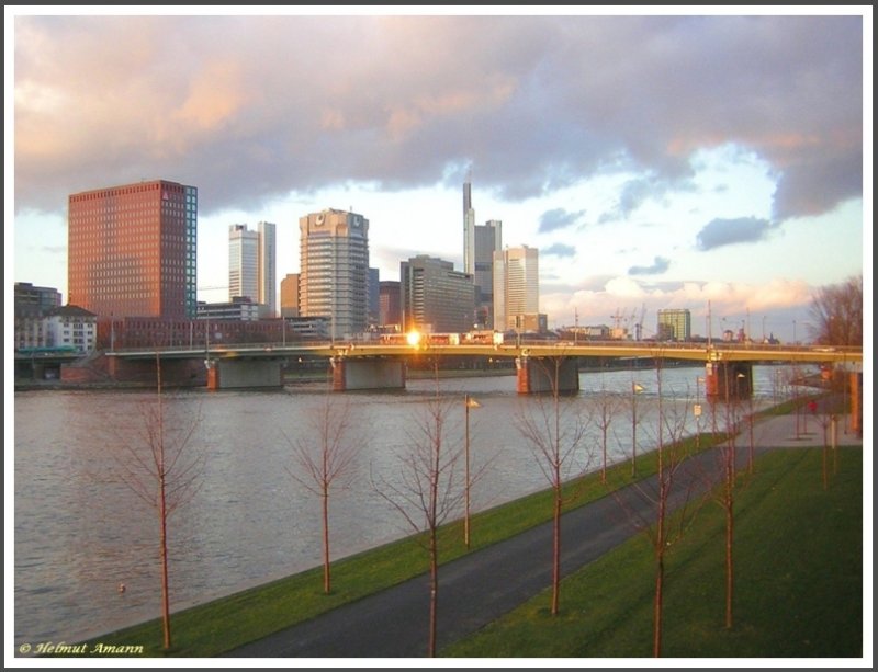 Blick auf die Friedensbrcke und einen Teil der Skyline von  Mainhattan  am 02.02.2008 im Abendlicht. Auf der Brcke fuhr gerade der  Ebbelwei-Express  die Stadtrundfahrt-Staenbahn von Frankfurt am Main und reflektierte die Abendsonne in einem Fenster. 