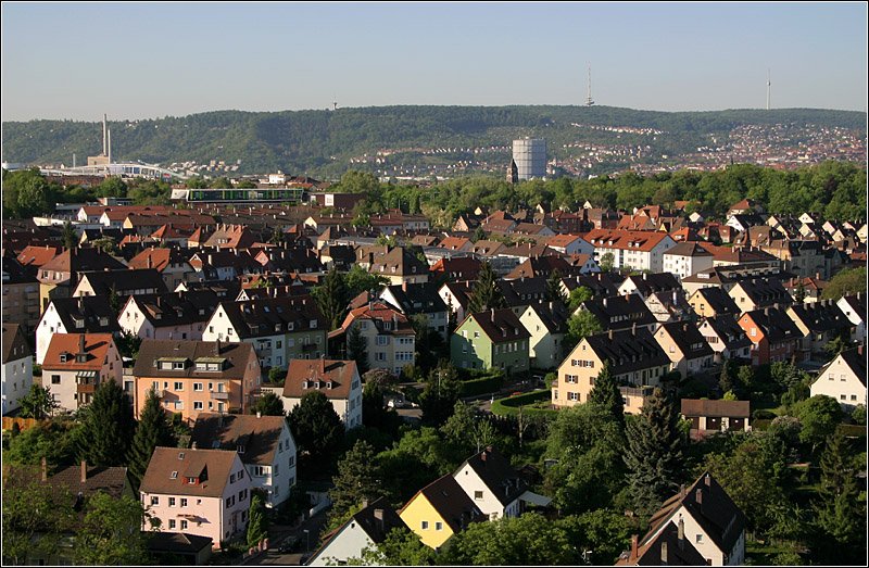 Blick von der Einsteinstrae aus ber die durch die Morgensonne angestrahlten Huser von Bad Cannstatt zu den bewaldeten Hngen der Stadt Stuttgart mit den drei Trmen (in der Mitte der Fernmeldturm auf dem Frauenkopf und rechts der berhmte Fernsehturm auf dem Hohen Bopser). Ganz links kann das silbern schimmernde Daimler-Museum noch erkannt werden, daneben das Daimlerstadion vor dem Kraftwerk Gaisburg. Rechts unterhalb die markante Aufstockung der Maybach-Schule. Rechts der Bildmitte der Gaskessel von Gaisburg. 2.5.2007 (Matthias)