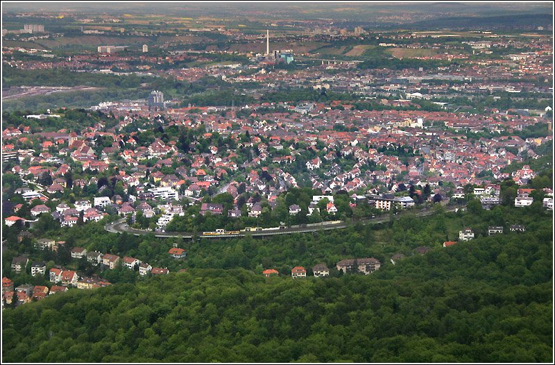 Blick vom Fernsehturm auf das Wohngebiet Gnsheide. Dahinter, dichter bebaut, liegt Ostheim. Oben in Bildmitte ist das Kraftwerk Mnster zu sehen. Rechts daneben das Neckartalviadukt der Gterumgehungsbahn. Links im oberen Drittel sind ein Teil der Abstellanlagen des Hauptbahnhofes zu erkennen.
Vorne am Rand der Bebauung fhrt eine Straenbahn der Linie 15 auf der Pischekstrae bergwrts.