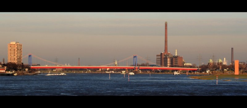 Blick vom Rheinufer in Duisburg-Homberg auf die Friedrich-Ebert-Brcke zwischen Duisburg-Ruhrort und -Homberg. 

Rechts ist die Skulptur bzw. Landmarke  Rheinorange  zu sehen. Dort fliet die Ruhr in den Rhein.

Links daneben die Brckentrme der  Homberger Brcke . Sie tauchten frher in der ein oder anderen Tatort-Folge mit Gtz George alias Schimanski auf, die u. a. in Duisburg-Ruhrort gedreht wurden.

Die groe Fabrik kann ich nicht zuordnen, die Infos reiche ich nach.

Links das Hochhaus beherbegt das Hotel Rheingarten in Homberg.