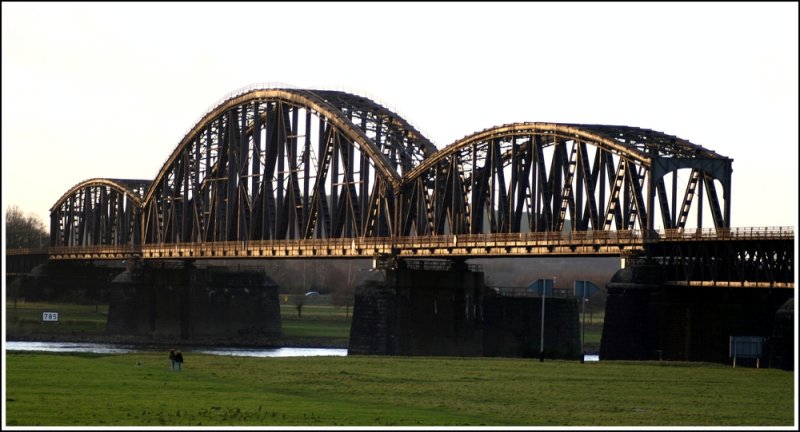 Blick ber die Rheinauen Duisburg-Beeckerwerth auf die Haus-Knipp-Brcke. Die Haus-Knipp-Eisenbahnbrcke ist eine Eisenbahnbrcke ber den Rhein nrdlich der Duisburg-Ruhrorter Hfen zwischen Duisburg-Beeckerwerth und Duisburg-Baerl im Verlauf der Strecke Oberhausen West - Neumhl - Meiderich Nord - Baerl und weiter nach Moers – Hohenbudberg.  Quelle: Wikipedia