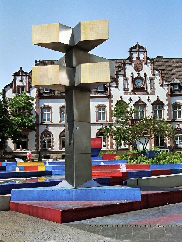 Brunnen auf dem Viktoriaplatz. Das neugotische Gebude im Hintergrund war einmal die Hauptpost, heute ist es das stdtische Kunstmuseum (25. Mai 1989). Der Brunnen wurde von dem Knstler Otto Herbert Hajek gestaltet. Die Meinungen darber sind geteilt. Es ist jedoch zu bercksichtigen, dass sich die Konzeption des Knstlers wohl nur bei der Draufsicht vllig erschliet, die aber allenfalls aus den umgebenden Husern mglich ist.