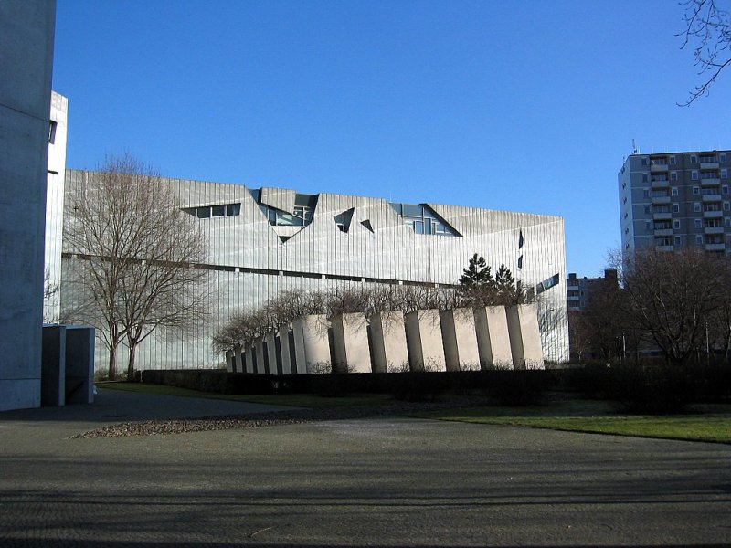 Das Jdische Museum, Bau von Libeskind 1997. Im Vordergrund der Stelengarten, im Hintergrund ein Teil des gezackten Monolithen, dessen metallene Aussenhaut viele Einschnitte und Schrammen aufweist.