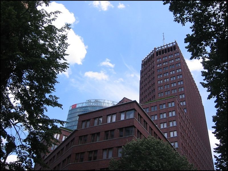 Der 103 Meter hohe Kollhoff-Tower am Potsdamer Platz erinnert sehr an ltere amerikanische Hochhuser. Im Hintergrund ist ein Teil der Spitze des BahnTowers zu sehen. (Juli 2005)