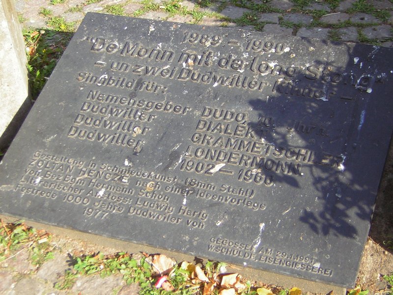 Dieses Foto zeigt:  De Monn mit de long Stong  -un zwei Dudwiller Kinner-
Nheres kann man auf dem Foto erkennen ( Eiserne Tafel.)Das Foto wurde auf dem Dudweiler Dudoplatz im Saarland aufgenommen.