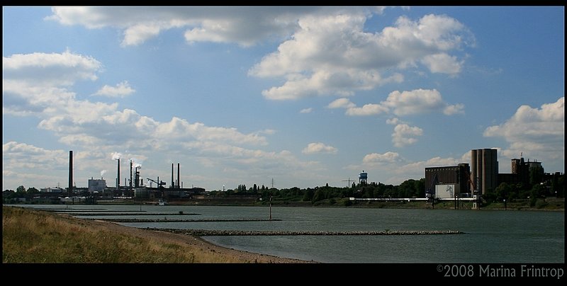 Duisburg-Neuenkamp - Blick über den Rhein auf die Plangemühle (rechts), den Wasserturm und die Chemiefabrik Sachtleben in Duisburg-Homberg.