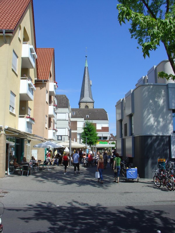 Ein Blick in die Fugngerzone des Stadtteils Rheda beweist, dass diese insbesondere an Markttagen viele Besucher anzieht. Im Hintergrund ist die ev. Stadtkirche zu sehen. Die Baugeschichte dieser Kirche lsst sich bis in das 14. Jahrhundert zurckverfolgen. Die gut erhaltene Frstenempore aus dem 18. Jahrhundert, eine Taufschssel aus dem Jahre 1616 und Reste des alten Gesthls mit geschnitzten Familienwappen und Hauszeichen sind noch zu besichtigen.  
