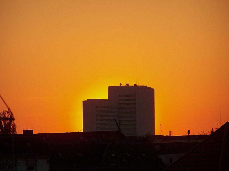 Ein Sonnenuntergang in Hamburg. Hier passt die Sonne haargenau hinter ein Mehrfamilienhaus.