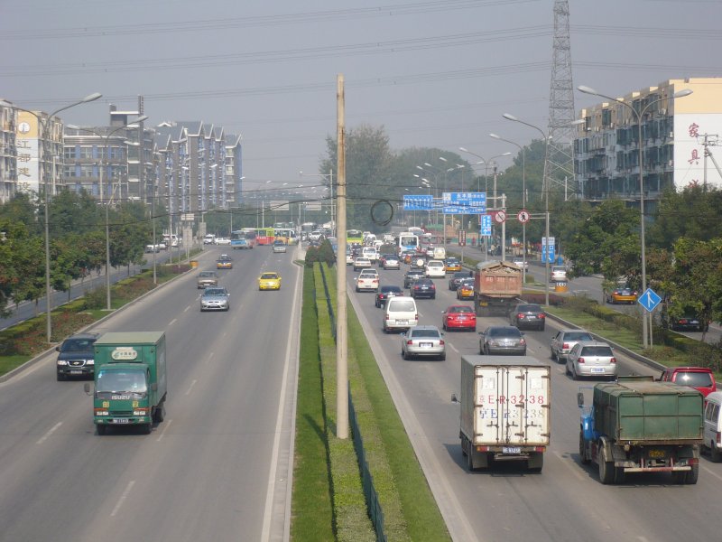 Eine der Ringstraen, die Peking umrunden. Wir waren hier vielleicht 10 km vom Stadtzentrum entfernt, aber dorthin zu kommen war gewhnungsbedrftig: Stehend in der schnellen, dafr berfllten U-Bahn oder berwiegend stehend mit dem Taxi im Straenverkehr - was schnell mal ber eine Stunde dauerte. Sitzend, aber kriechend langsam - motorisierter Verkehr mit seinen kuriosen Auswchsen. Interessant waren immer die Fahrzeuge - so erinnere ich mich an einen rostigen Lkw auf der Autobahn, dessen hintere Stostange nur noch an einer Strebe hielt, und das sicher nicht mehr lange. 2007