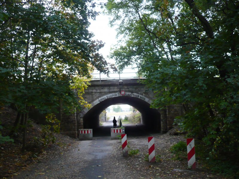 Eisenbahnunterfhrung zwischen der Neubausiedlung Carlsgarten und der Verlngerten Waldowallee. Frher war die Fahrbahn hier nicht asphaltiert und besonders nach Regengssen stark verschlammt. Vor wenigen Jahren kam auf einer Seite eine autobreite Asphaltschicht hinzu - damit begannen unvorhergesehene Probleme. Als Fugnger oder Radfahrer wurde man gerne dezent in den Schlamm verwiesen, ein Warten oder Hinterherfahren in Schrittgeschwindigkeit war nur wenigen mglich. Das fhrte zu einigen Beschwerden bei der zustndigen Behrde. Vor einigen Monaten hat man nun die Strae fr den Autoverkehr gesperrt, sie bleibt weiterhin Fugngern und Radfahrern erhalten. Langfristig will man hier eine echte Strae bauen. 6.10.2009