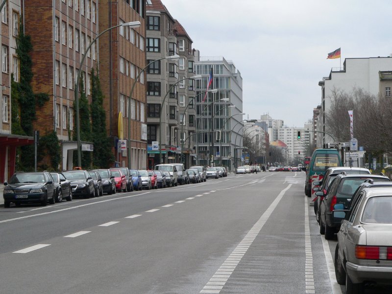 Es gibt zwei Arten von Fahrradstreifen. Dies hier ist die  freiwillige  Variante, die von Pkw mitgenutzt werden darf. Die andere Variante htte eine durchgezogene Linie und keine rechts parkenden Pkw, sowie ein blaues Radwegschild. Hier fhrt man am besten sehr weit links, das Lenkerende schon fast ber die linke Markierung herausragend. Sonst gefhrdet man sich selbst durch ffnende Tren. Vorstehende Fahrzeuge wie den VW-Bus ganz vorne umfhrt man, wenn mglich, nicht mehr auf dem Radstreifen - oder nur langsam. Hier besteht Gefahr durch unerwartet hervortretende Fugnger. Berlin Wilhelmstrae, 18.3.2007