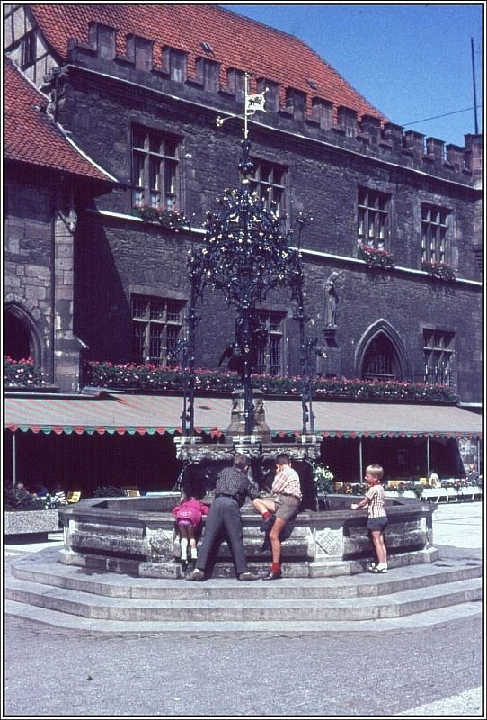 Hier sieht man dem Gttinger Marktplatz mit dem Gnselieselbrunnen und dem alten Rathaus im Hintergrund, aufgenommen vermutlich Anfang der 70er Jahre des letzten Jahrhunderts. Beim Vergleich mit dem vorherigen Foto erkennt man, dass der Marktplatz (im Zuge der Einrichtung einer Fugngerzone) umgestaltet wurde, wobei der Gnselieselbrunnen etwas in sdlich Richtung versetzt wurde. Das alte Rathaus wurde ab ca. 1270 errichtet und war bis 1978 Sitz des Rates und der Verwaltung der Stadt Gttingen. (Dia-Archiv Alfred Schmidt)