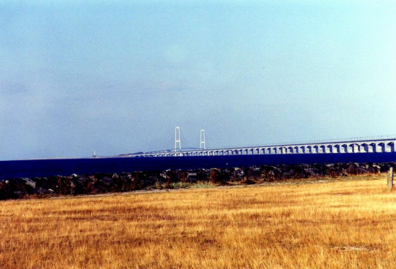 Hierbei handelt es sich um die Storebeltbrcke zwischen der Insel Fnen und der Insel Seeland. Der Auftrag zum Bau der Brcke ber den Groen Belt(Storebelt) wurde am 12. Juni 1986 vom dnischen Parlament erteilt. Am 14 Juni 1998 wurde das Bauwerk fr den Verkehr freigegeben. Von der Insel Fnen aus, bei der Stadt Nyborg, fhrt zuerst eine knapp 7 Km lange Auto-und Eisenbahnbrcke auf die kleine Insel Sprog. Die Strae besitzt jeweils 2 Fahrspuren in jede Richtung und die Bahntrasse verluft zweigleisig. Von der Insel Sprog aus berquert die Autobahn mit einer weiteren knapp 7 Km langen Brcke die Ostsee bis zur Insel Seeland, nahe der Stadt Korsr, whrend die Bahntrasse ab der Insel Sprog in einem 8 Km langen Bahntunnel bis zur Insel Seeland verschwindet. Die beiden Pylonen des Brckenteils von Sprog nach Seeland bilden mit knapp 250m den hchsten Punkt Dnemarks. Bei sehr extremen Wetterbedingungen kann es passieren das die Brcke fr den Verkehr zeitweise gesperrt werden muss. Das Bild enstand bei Nyborg auf Fnen (gescanntes Bild)