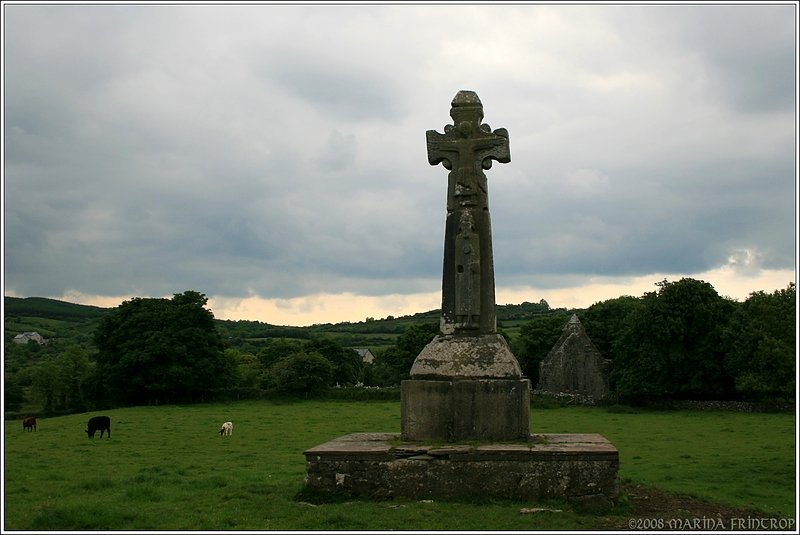 Impressionen vom Dysert o'Dea Archaeology Trail, Irland Co. Clare. St. Tola's Highcross aus dem 12. Jahrhundert (Wiederaufbau durch Conor O’Dea im Jahre 1683. Die Ostansicht zeigt die Kreuzigung des Bischofs St. Tola. Rechts neben dem Sockel erkennt man im Hintergrund schon die Kirche.