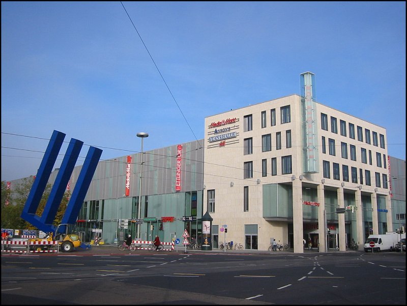 In den Jahren 2003 bis 2005 wurde in Karlsruhe am Rande der Innenstadt ein groes Einkaufszentrum gebaut, fr das eine groe Flche freigerumt werden musste. Dieses Bild stammt vom 27.10.2005, die Erffnung liegt nun schon etwas zurck. Aufnahmestandort ist wieder der Ettlinger-Tor-Platz. Das Einkaufszentrum, das auch den Namen  Ettlinger Tor  trgt, ist viel zu gro, um es komplett auf ein Bild zu bekommen. Es bietet rund 130 Geschften und Gastronomiebetrieben eine Flche von ca. 33.000 qm. Von den Proportionen und der Formgebung her erinnert es durchaus an den alten Gebudebestand an, der sich hier einst befunden hat. Ob es die Stadt wirklich weiter bringt wird wohl erst die Zukunft zeigen knnen, allerdings muss ich zugeben, dass ich oft durchgeschlendert bin, als ich noch in Karlsruhe gewohnt habe. 