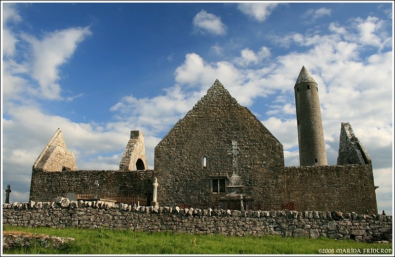 Klostersiedlung Kilmacduagh - Rckseite der Kathedrale (tlw. aus dem 11. Jahrhundert) mit einigen Grbern und dem Rundturm aus dem 12. Jahrhundert. Irland Co. Galway in der Nhe von Gort.