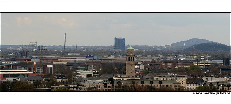 Mlheim an der Ruhr - Blick vom Bismarckturm. Vorn in der Mitte der Rathausturm von Mlheim, dahinter links der Gasometer in Oberhausen. Vom Rathausturm aus gesehen befinden sich im Hintergrund auf der linken Seite die Mannesmann (heute auch Europipe und Valorec)-Werke. Im Verlauf nach rechts schliet sich das Werk der Siemens Power Generation an, zu dem auch der Khlturm rechts am Bildrand gehrt. Unmittelbar rechts etwas hinter dem Rathausturm ist das ehemalige Verwaltungsgebude der KWU AG zu sehen (heute Haus der Wirtschaft) mit bergang zur Hauptverwaltung von Mannesmann.