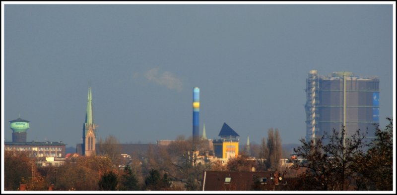 Oberhausen/Rheinland - Faszination Tele-Objektiv... Das Foto wurde aus dem Hafengebiet in Mlheim aufgenommen. Rechts der Gasometer (Entfernung ca. 6 km). Weiter links der Kirchturm gehrt zu der Pfarre am St.-Josef-Hospital und links am Bildrand ist der RWW-Wasserturm an der Mlheimer Strae (kurz vor der Kreuzung Duisburger Strae) zu sehen. 