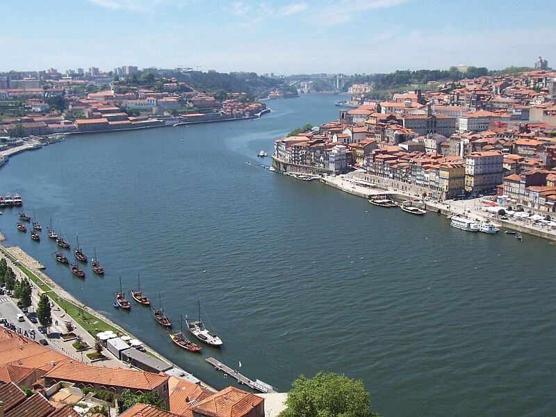 Rechts das Centrum von Porto, links der Stadtteil Vila Nova de Gaia, in der Mitte der Douro in Richtung Westen (Atlantik). Links unten alte Weinschiffe, die Portwein den Douro herab nach Porto befrdert haben, dabei soll manches Schiff und Weinfa zu Bruch gegangen sein, weil der Douro gefhrliche Klippen im Strom hatte, heute ist er durch drei Schleusen problemlos. Aufgenommen im Mai 2006