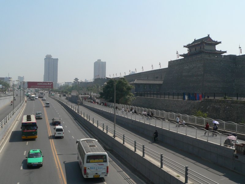 Riesige Verkehrsstraen vor der Stadtmauer von Xi'an. Interessantes Detail: Wegen der Sonnenstrahlung trgt ein Fugnger einen Regenschirm. 09/2007