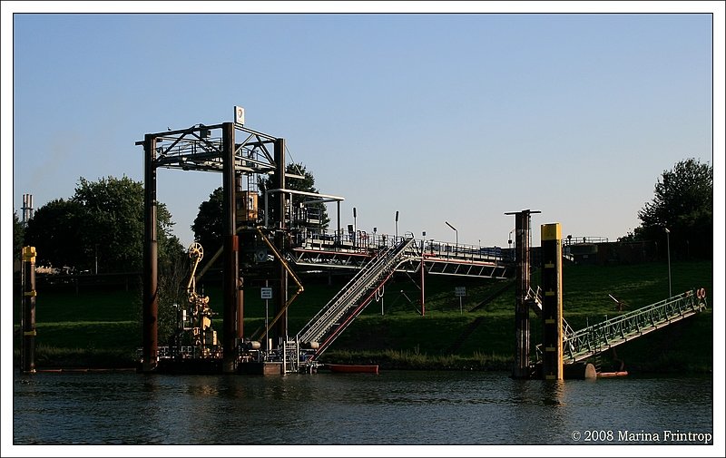 Schiffs-Entladestation an der Ruhr von Total in Duisburg-Neuenkamp.  Das Tanklager Duisburg ist eines von neun Lagern, die TOTAL in Deutschland unterhlt. Im Tanklager, das rund 400 Tankstellen in der Region sowie den Brennstoffhandel versorgt, werden jhrlich ca. 1,3 Millionen Tonnen Kraftstoffe und Heizl umgeschlagen. Auerdem steuert die Tochtergesellschaft TOTAL Minerall GmbH von Duisburg aus den bundesweiten Vertrieb von Heizl.  Quelle: www.brennstoffspiegel.de