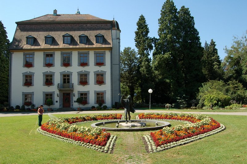 Schlo Schnau - Eine fleiige Grtnerin sorgt dafr, da die wunderbaren Blumenrabatte in der Julisonne nicht vertrocknen. In der Mitte der Trompeter von Sckingen, der die Stadt bekannt gemacht hat. 18.7.2006