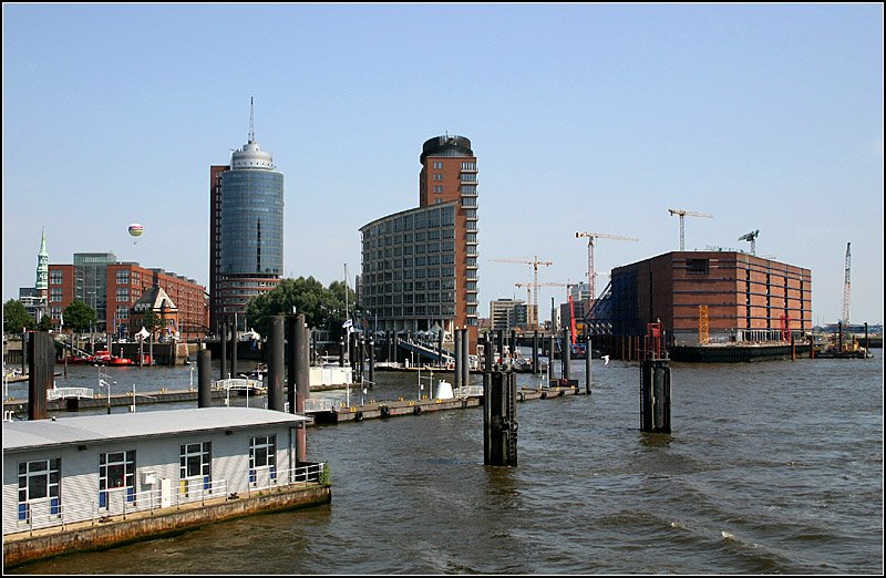 Stdtebaulich gelungener Abschluss der Speicherstadt nach Westen zum Hafen hin mit den Hochhusern auf der Kehrwiederspitze (Hanseatic Trade Center) und am Sandtorhft. Ein weiterer Hochbau entsteht auf dem alten Speicher rechts mit der Elbphilharmonie. Dahinter bei den Baukrnen wchst die Hafen City empor. 15.7.2007 (Matthias)