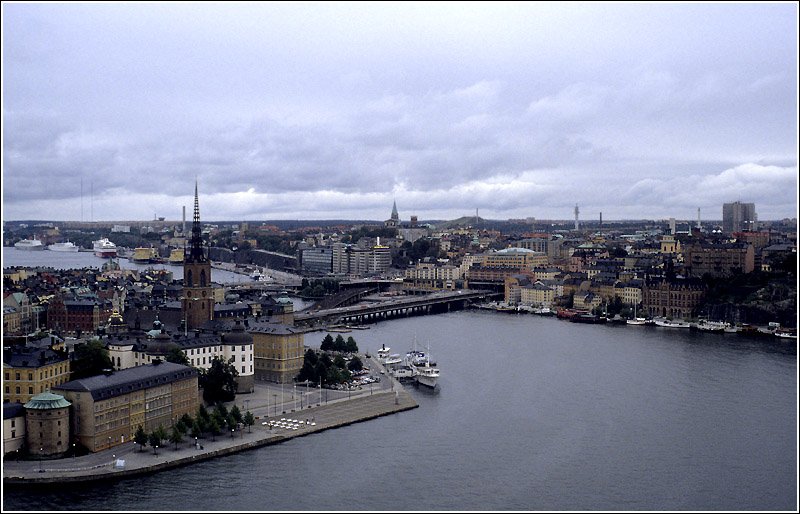 Stockholm vom Turm des Stadshuset aus gesehen: Im Vordergrund der Riddarfjrden, links Riddarholmen, dahinter Gamla Stan, die Altstadt von Stockholm. Die Brcken fhren von dort zum Stadtteil Sdermalm im Hintergrund. Scan vom Dia, 1990 (Matthias)