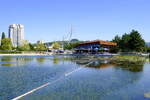 Lahr, Blick von der Brcke ber den Stegmattensee auf das Restaurant  Haus am See , dahinter der 50m hohe Pylon der Fu-und Radweg Brcke, alles errichtet zur Landesgartenschau