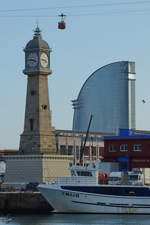 Der Leuchturm mit Turmuhr  Torre del Rellotge  wurde 1772 erbaut, dahinter das weit modernere Hotel Vela.