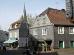 Zwei mit Schieferplatten verkleidete Huser und ein Kirchturm in Langenberg (Velbert).