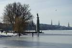 Hamburg-Hohenfelde am 14.2.2021: Blick auf die Alsterwiese Schwanenwik mit dem Denkmal „Drei Mnner im Boot“, weiterhin die sorglosen Mitbrger auf dem nicht freigegebenen Eis