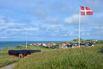 Die d�nische Flagge �Dannebrog� mit dem nordj�tl�ndischen Badeort L�nstrup im Hintergrund.
