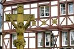 Doppel-Korpus-Kreuz mit Fachwerk im Hintergrund in der Rmerstrae in Bernkastel-Kues.