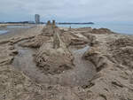 Blick auf eine Sandburg auf dem Priwall, im Hintergrund die markante Strandpromenade von Travemnde.