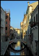 Eine kleine Brcke fhrt ber den Rio San Felice in Venedig und spiegelt sich im Wasser des Kanals.