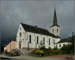 Die Kirche von Tarchamps vor einem dramatischen Himmel.