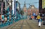 Amsterdam -  Damrak , Geschäftsstraße und im Hintergrund der Bahnhof.