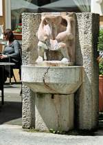 Als Brunnenfigur hält ein wasserspeiender Gnom zwei Fische.