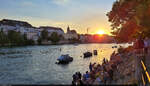 Während die Sonne verschwindet, herrscht am Rheinufer in Basel (CH) noch reges Treiben.