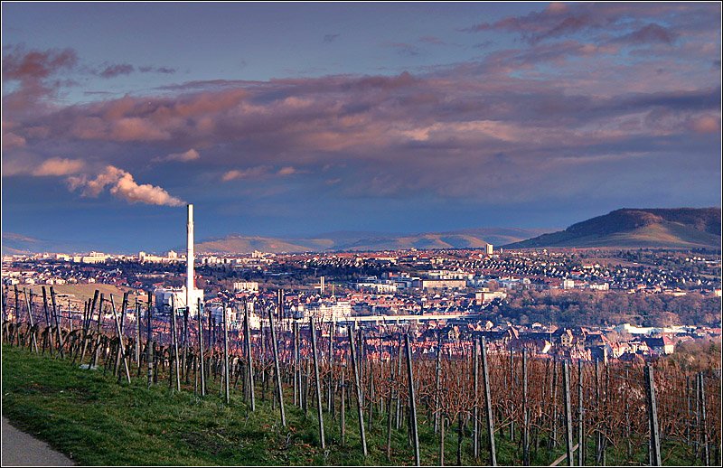 Versehntlich ist ein Gterzug mit auf Bild geraten. Dieser fhrt gerade ber das Neckartalviadukt, erkennbar in Bildmitte. Der Blick geht hier vom Burgholzhof nach Osten ber Bad Cannstatt hinweg ins Remstal. Der Berg rechts nennt sich Kappelberg, dieser befindet sich ber der Stadt Fellbach. Links der Kamin des Kraftwerks Mnster. So ein Bauwerk ist immer auch eine Landmarke und ist fr eine solche Aufnahme zudem von bildgestalterischer Bedeutung. 4.1.2007 (Matthias)