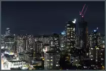 Die Skyline der Downtown von Vancouver bei Nacht, aufgenommen aus dem Blue Horizon Hotel. Am linken Bildrand verl�uft die Robson Street. Recht ist das im Bau befindliche Hochhaus  The Butterfly  zu sehen. (Vancouver, 15.10.2022)